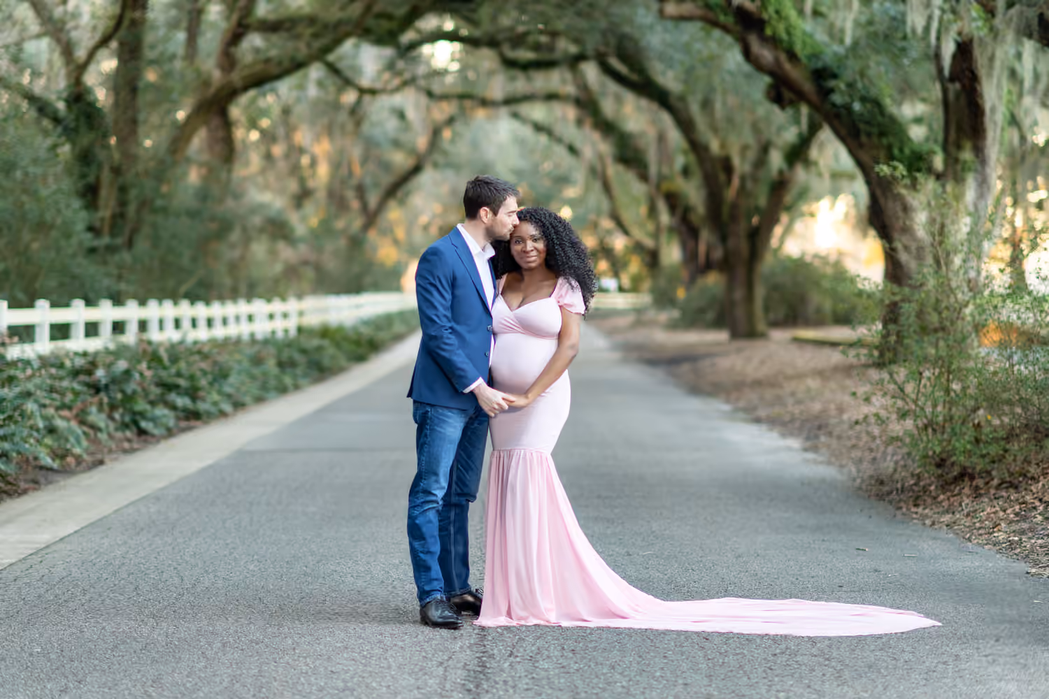 Couple embracing beneath moss-covered oak trees at Caledonia Golf and Fish Club.