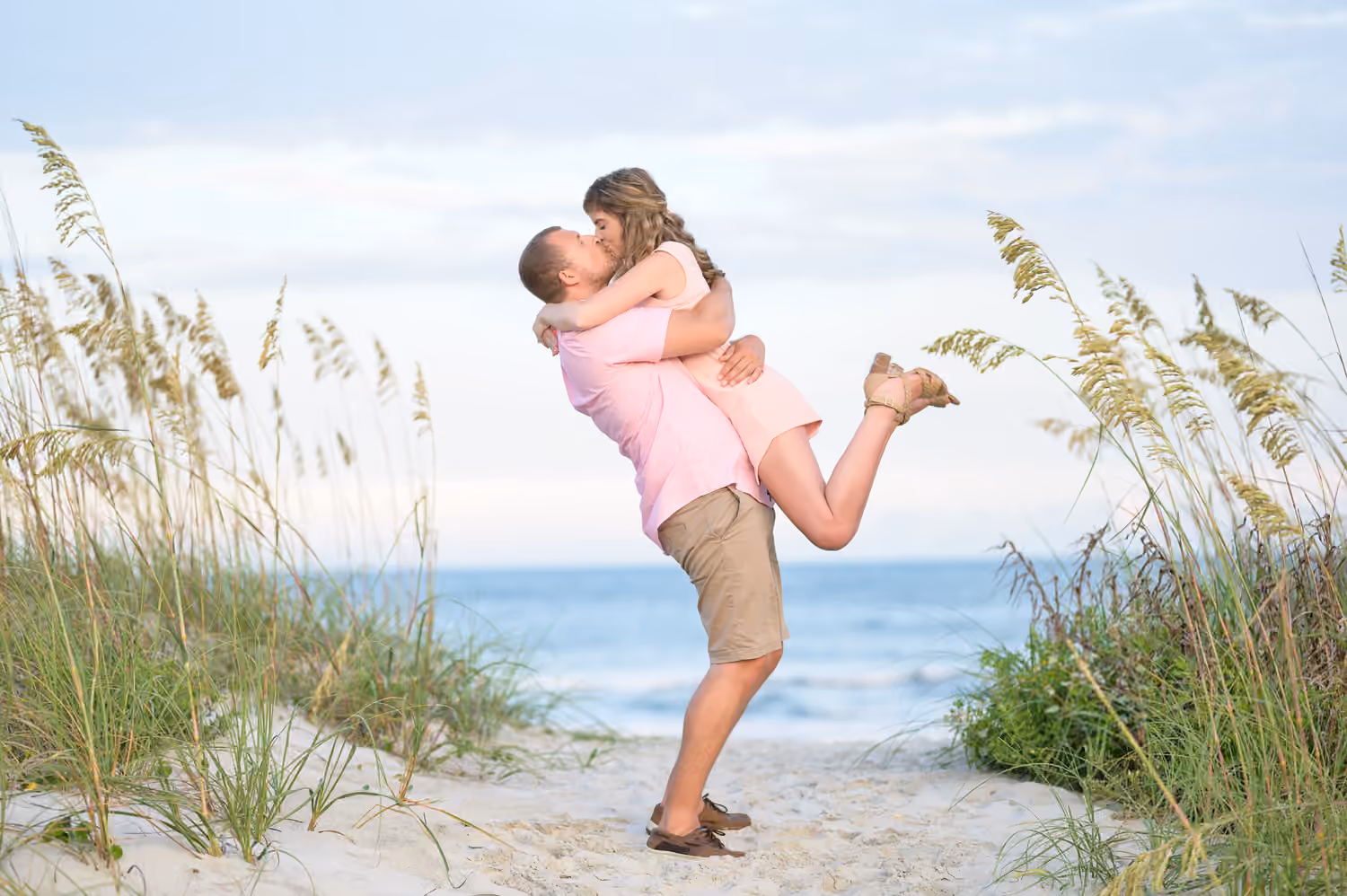 Couple sharing a kiss beside the sea oats at Huntington Beach State Park.