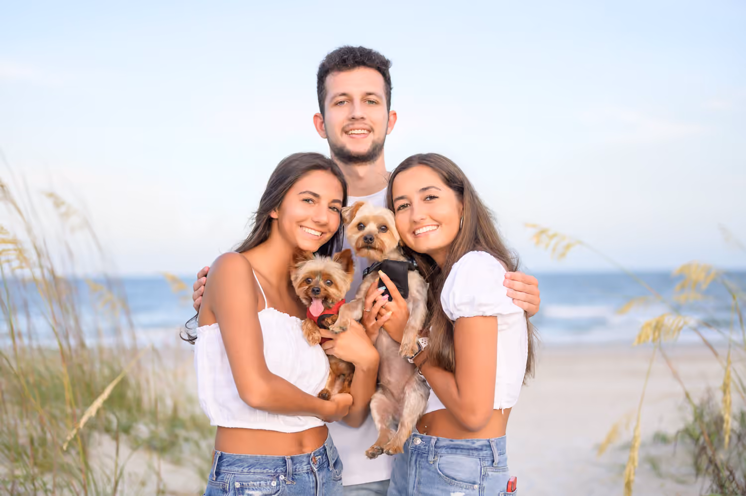 Three siblings with their dogs on the beach at Huntington Beach State Park.