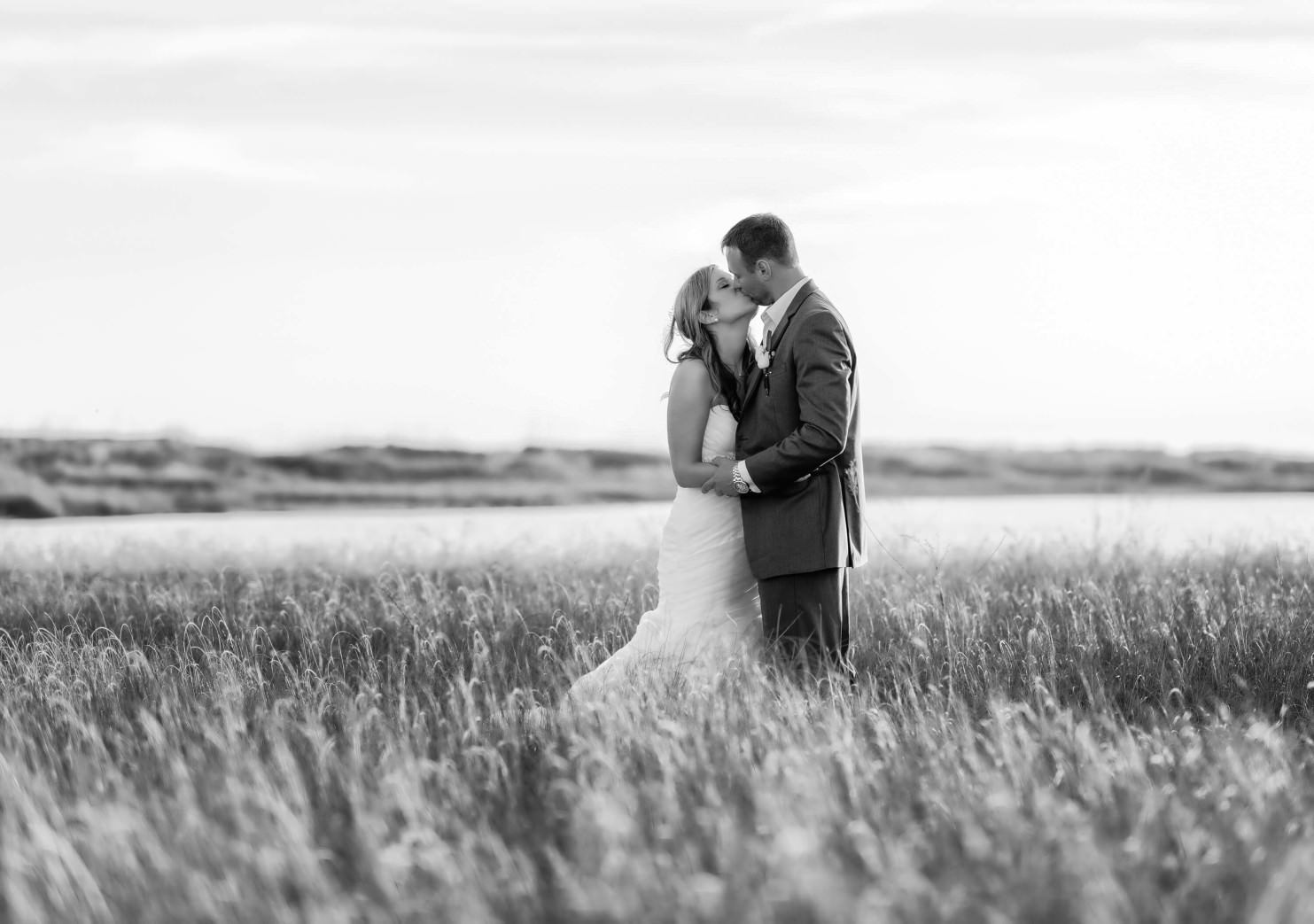 black-and-white-of-couple-kissing-with-sunlight-reflecting-on-the-beach-grass-holden-beach-1484x1043.jpg