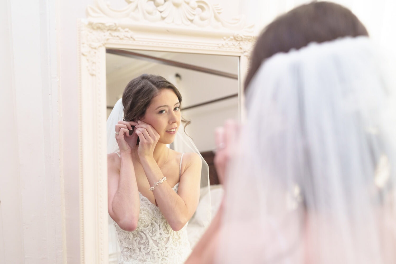 Bride putting on her earrings in the mirror - Tanglewood Plantation