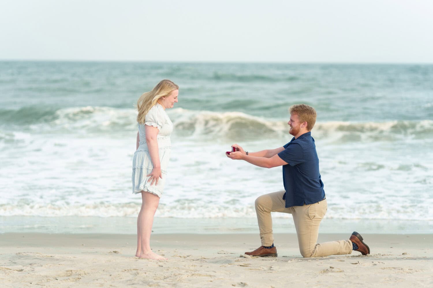 Showing her the ring by the ocean -