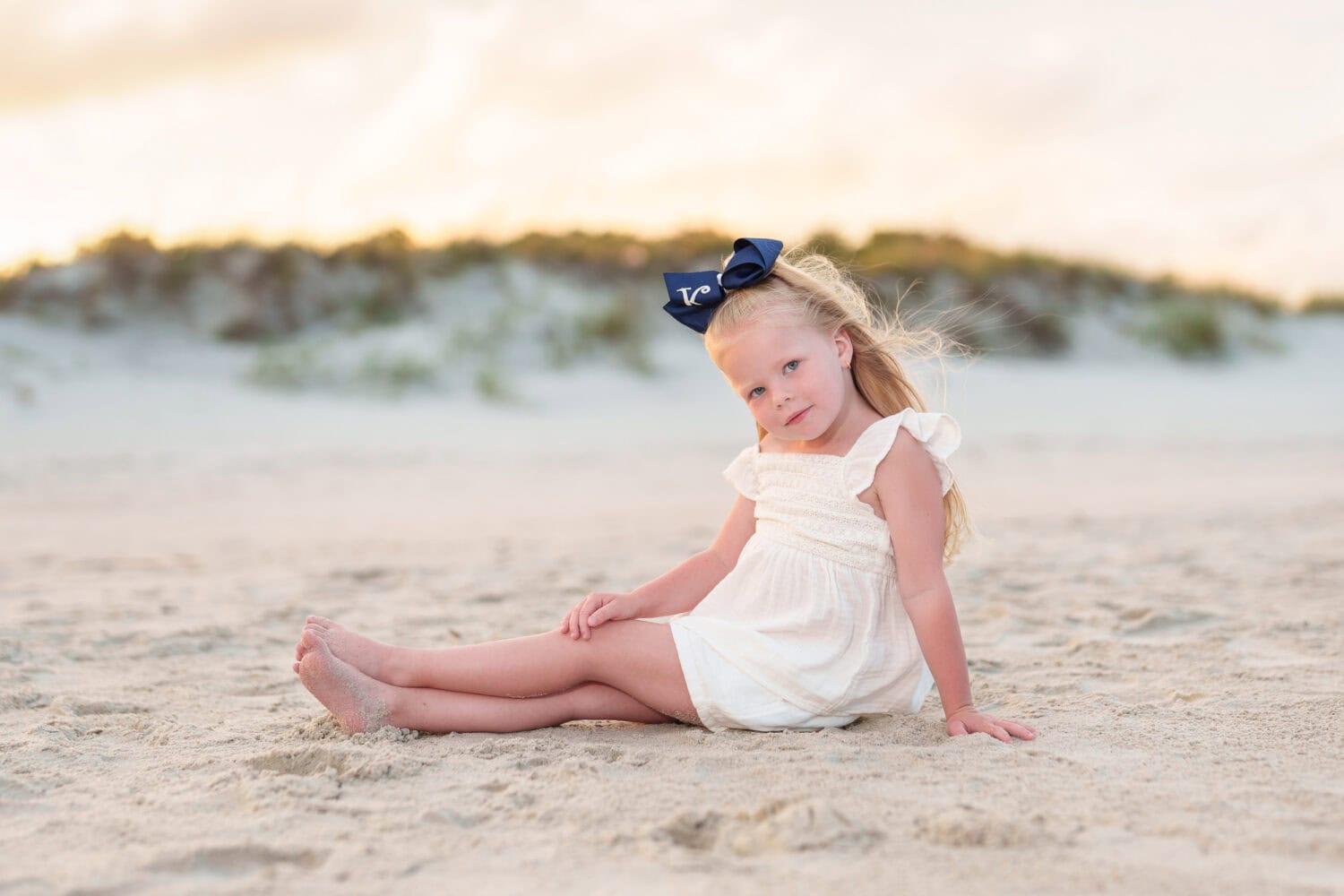 Little girl sitting in front of the dunes at sunset - Huntington Beach State Park