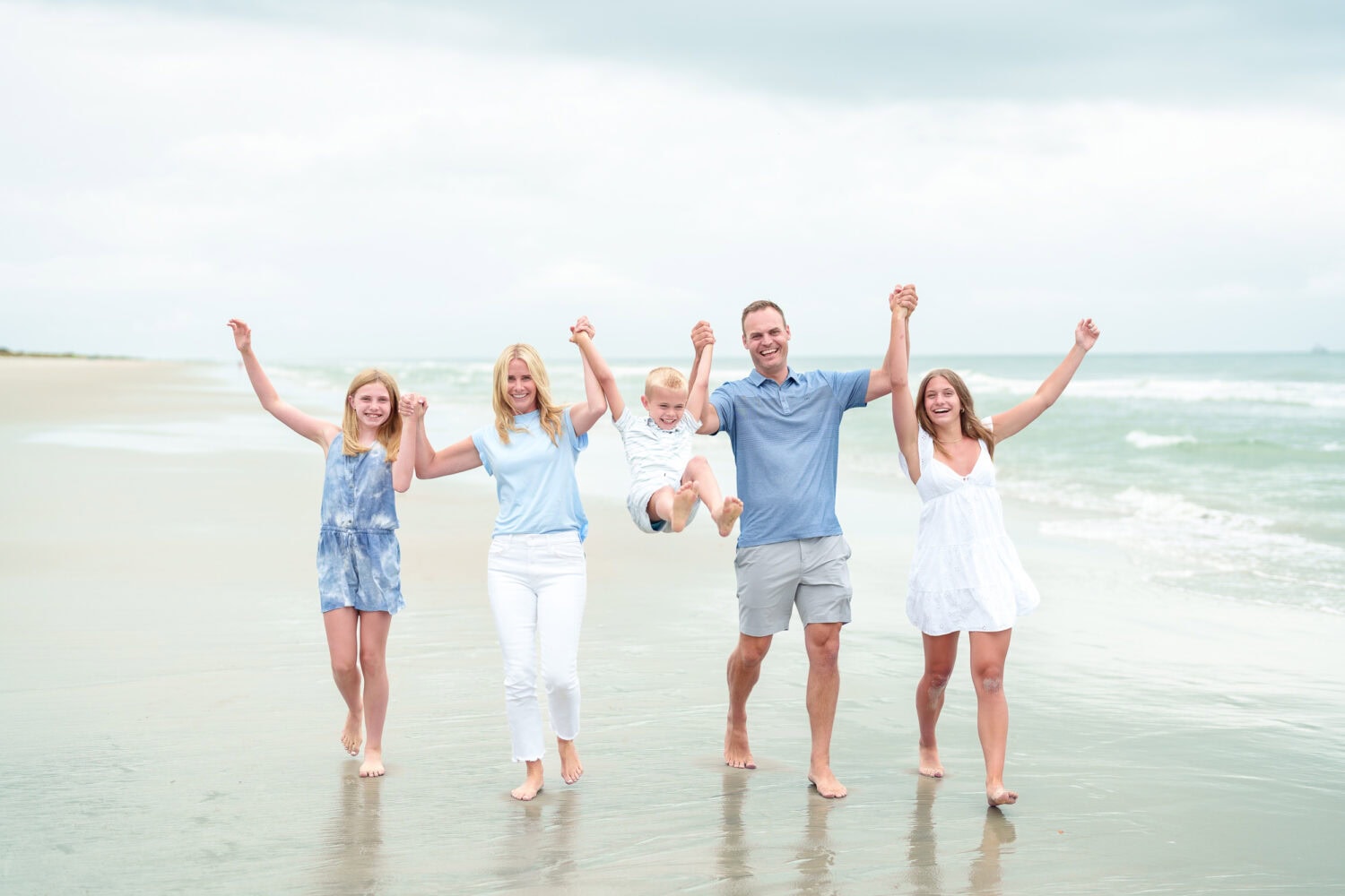 Happy family of 5 having fun walking down the beach together - Huntington Beach State Park