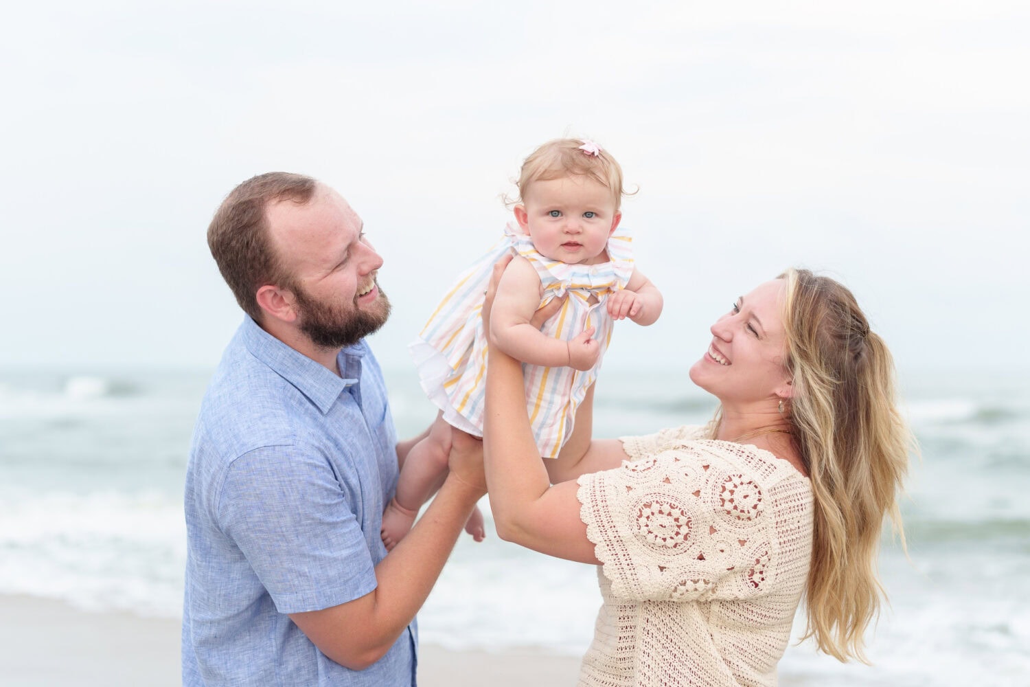 Mom and dad holding baby in the air - Huntington Beach State Park