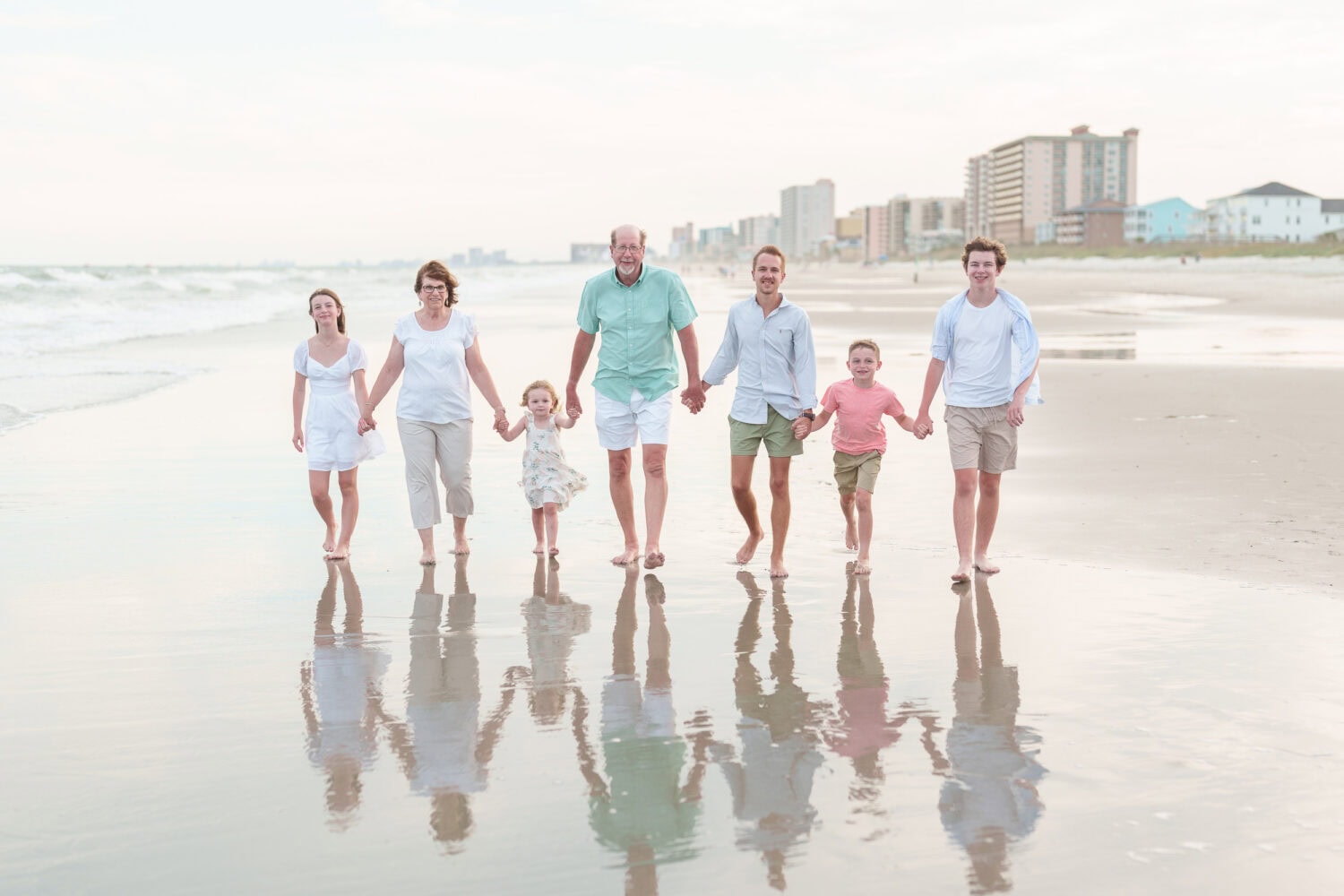 Big family walking down the beach with hotels in the background - Myrtle Beach