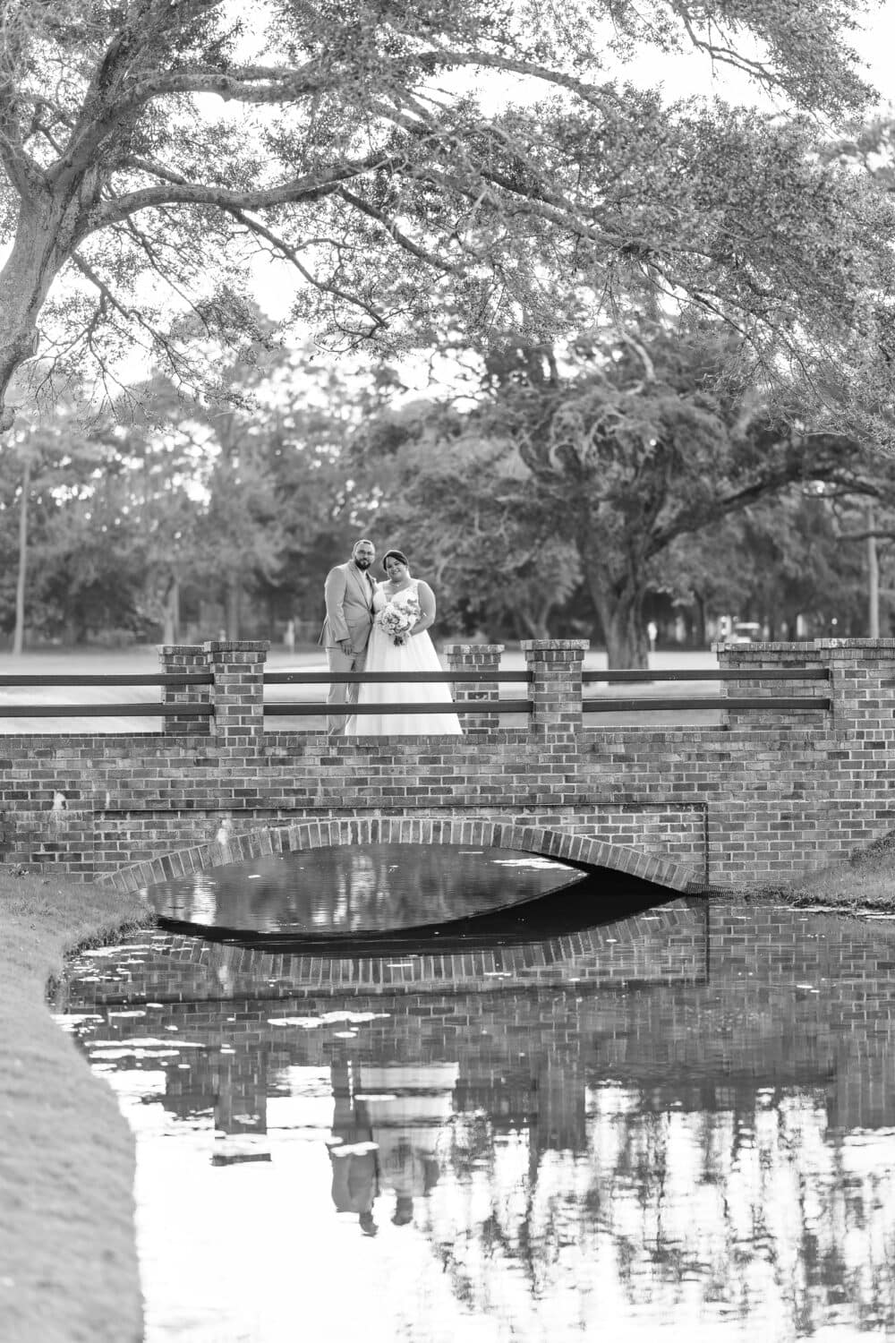 Bride and groom on the bridge reflecting in the water - Dunes Golf & Beach Club