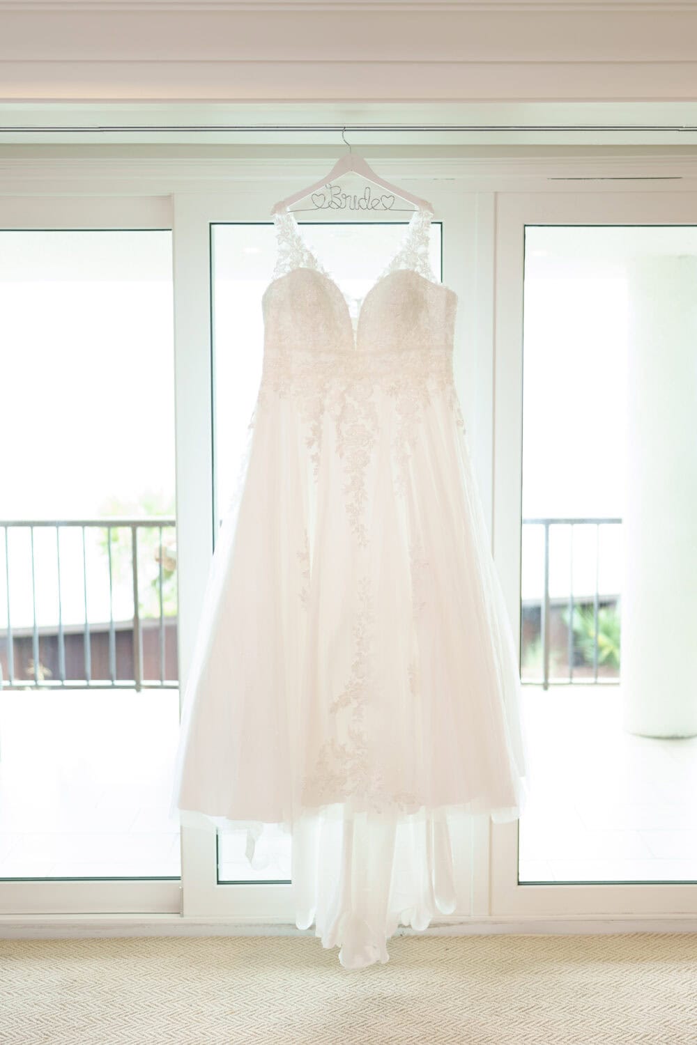 Bride's dress hanging in the window - Dunes Golf & Beach Club