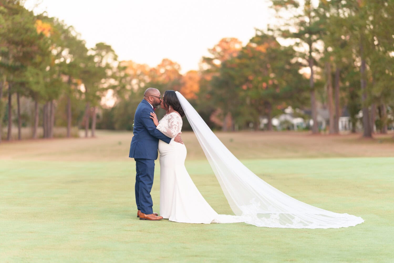 Kiss on the golf course with the veil flowing behind her - Wedgefield Country Club