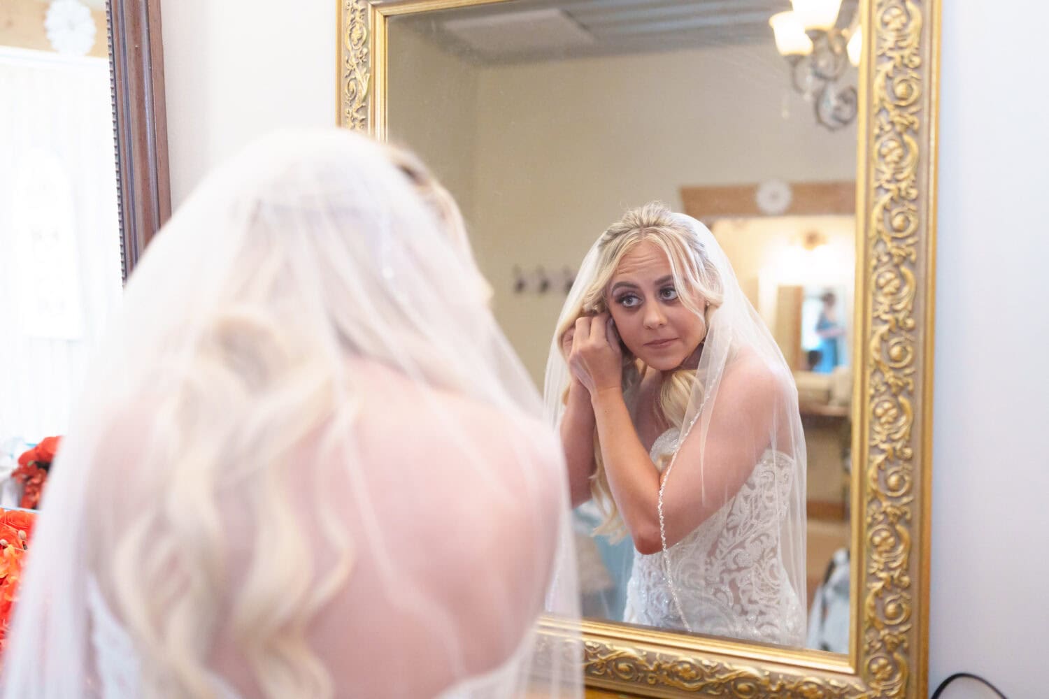 Bride putting earrings on in the mirror - Wildhorse at Parker Farms